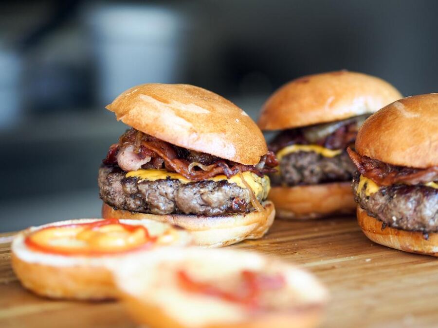Three smash burgers on a wooden board